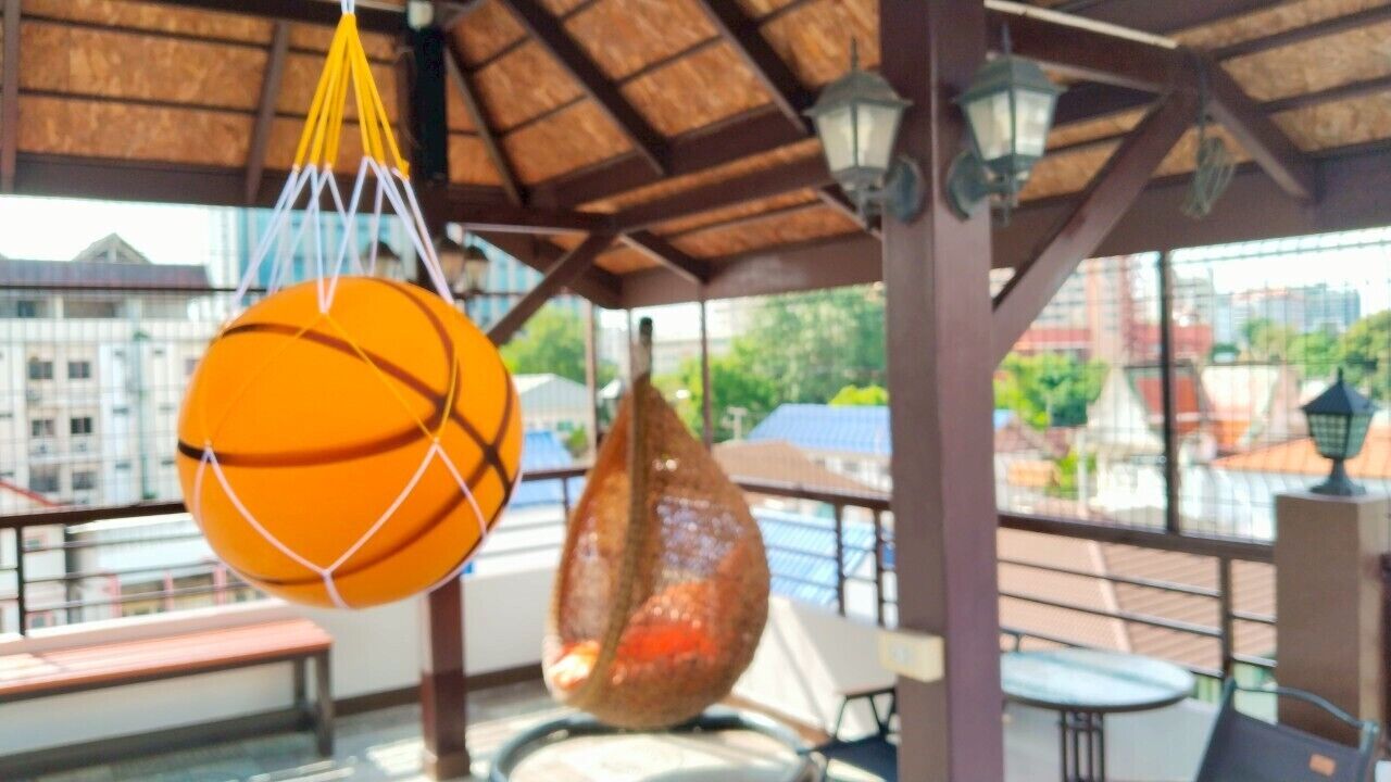 A covered outdoor seating area with a hanging basketball and a decorative object.