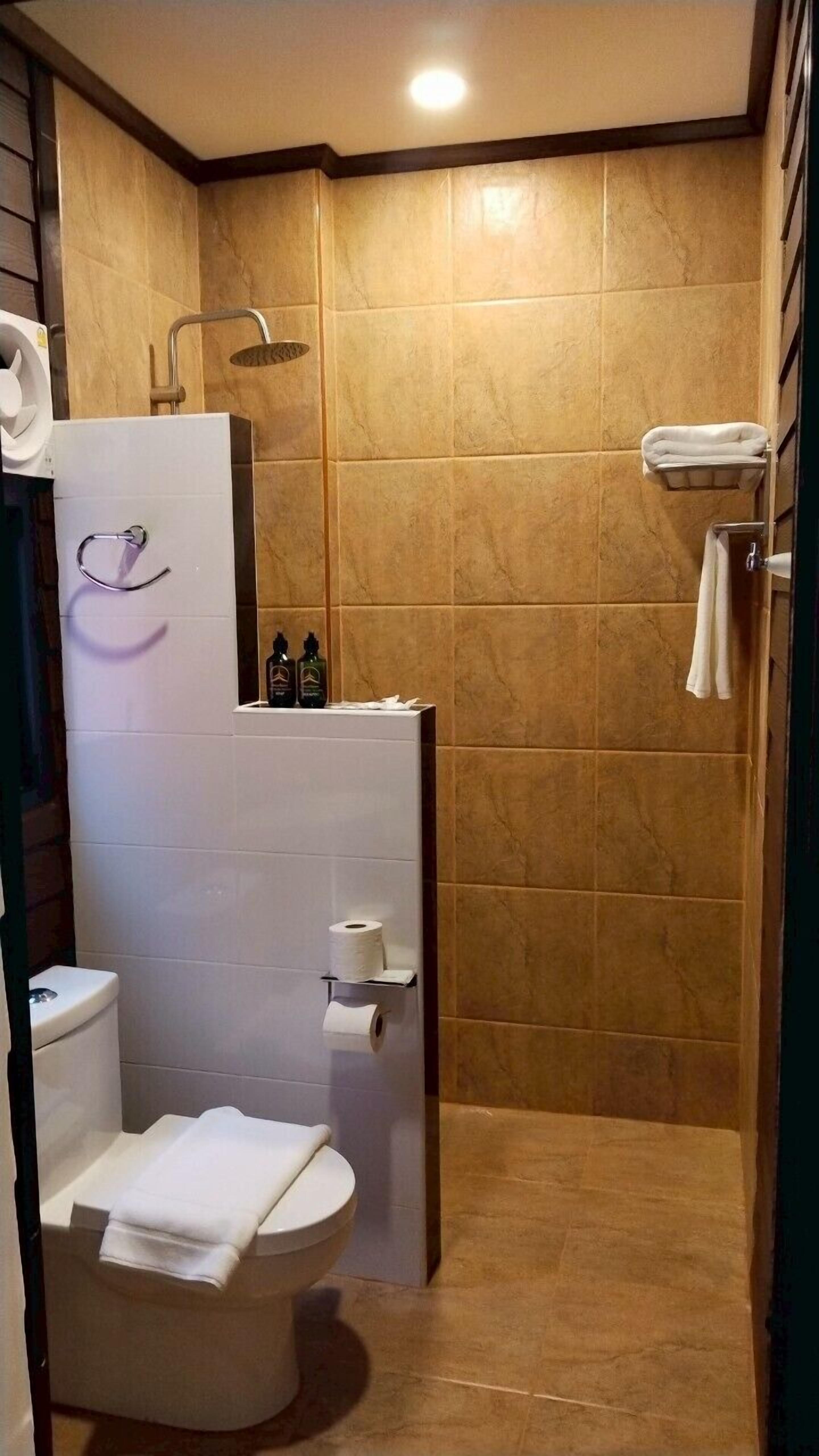 A bathroom with a toilet, a shower, and a towel rack.