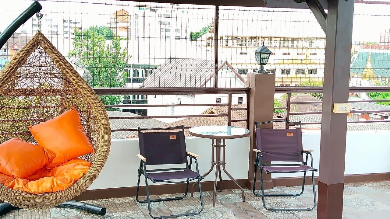 Un balcón con una hamaca colgante, dos sillas y una mesita.