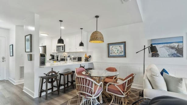 Een moderne keuken met witte kastjes, een centraal eiland en hanglampen.