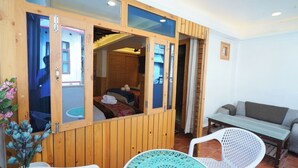 A wooden room with a bed, a small table, and a sofa. - Lord Krishna Boutique Stay (Dharamshala)