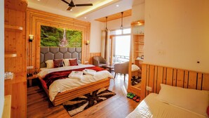 A spacious bedroom with a large bed, a ceiling fan, and a view of a waterfall through a large window. - Lord Krishna Boutique Stay (Dharamshala)