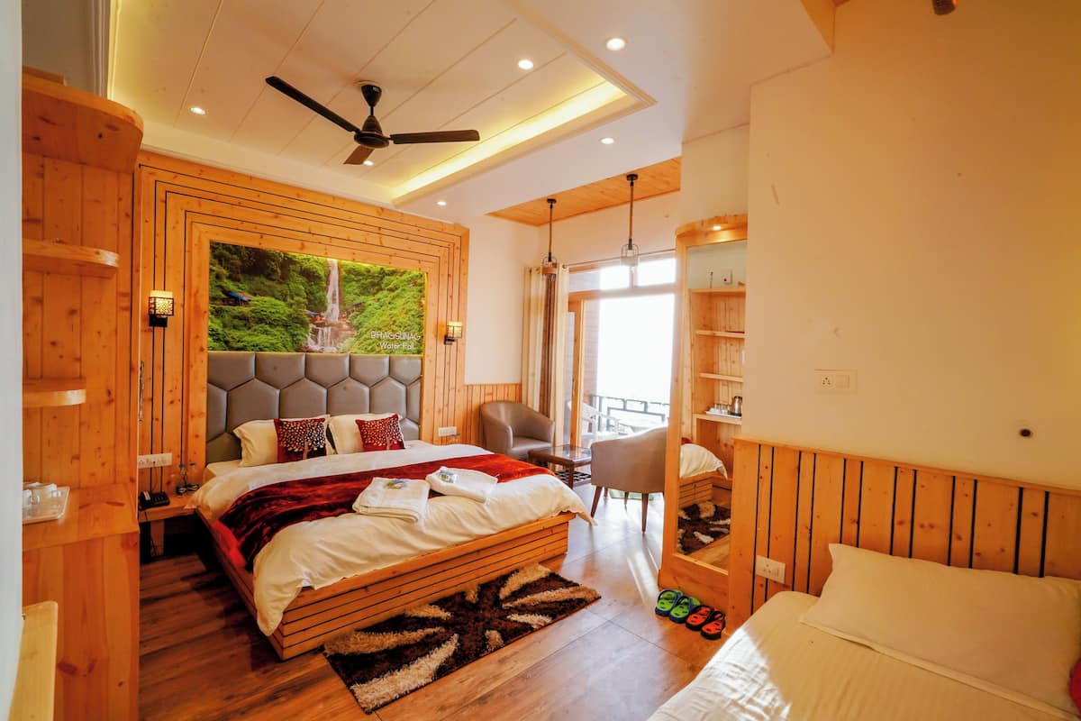 A spacious bedroom with a large bed, a ceiling fan, and a view of a waterfall through a large window.