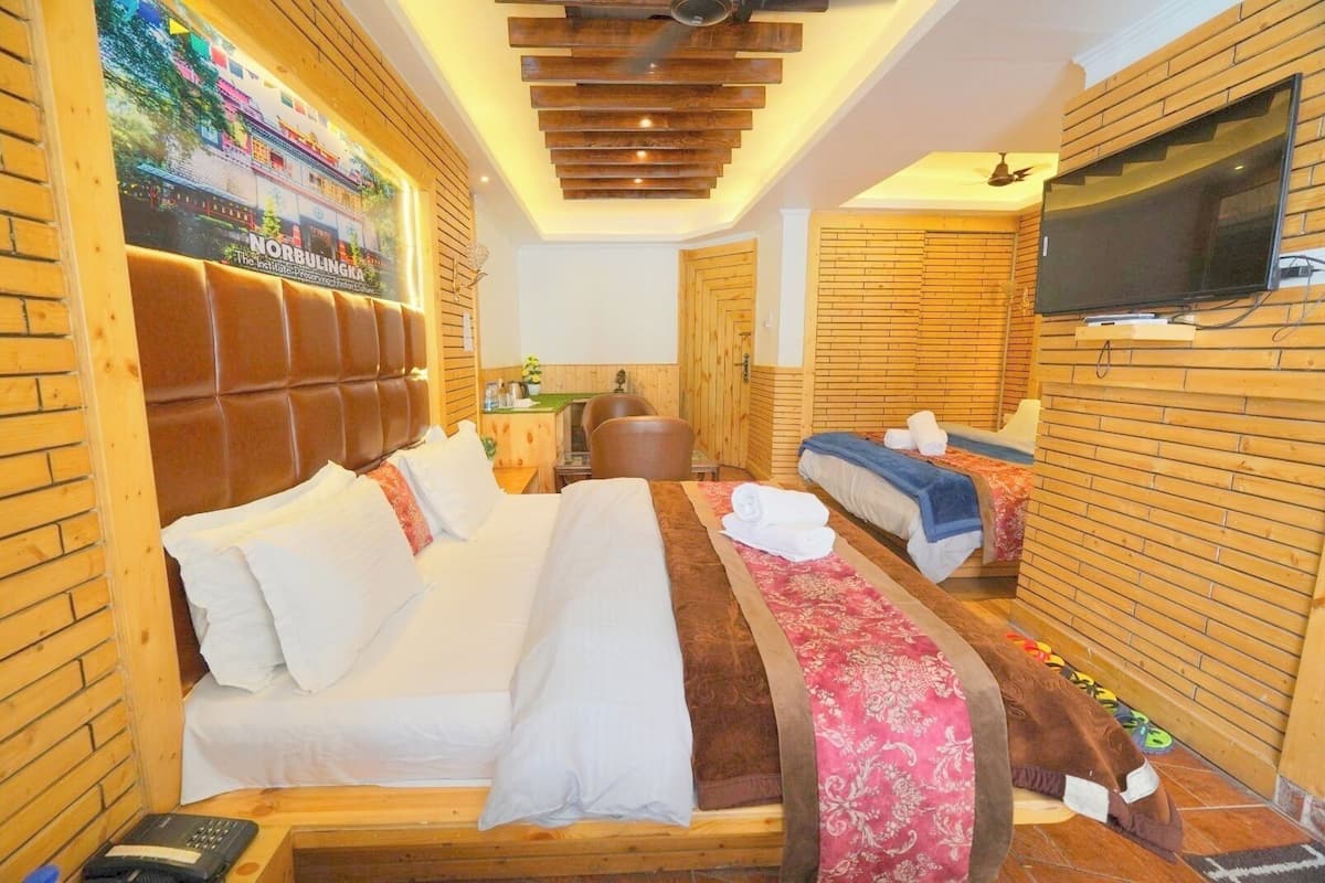 A hotel room with a large bed, a smaller bed, a TV, and a wooden wall design.