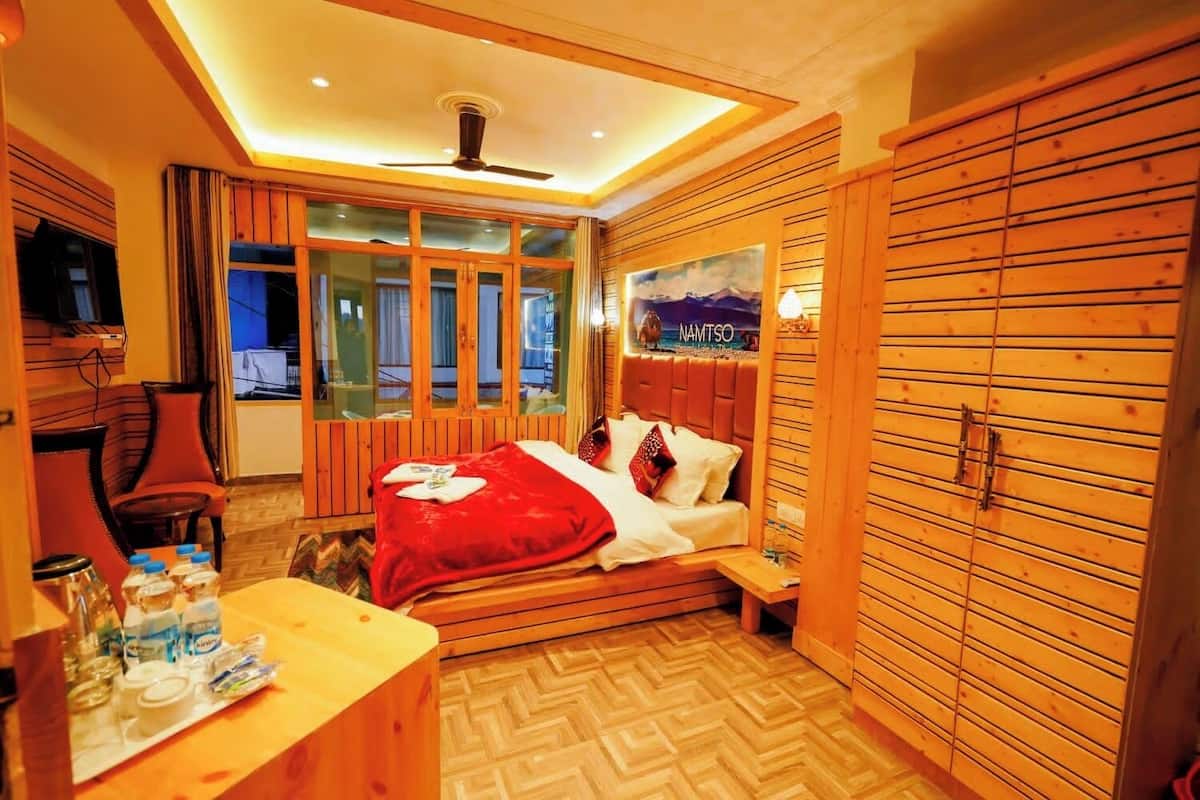 A cozy room with a bed, wooden wardrobe, and a desk with toiletries.