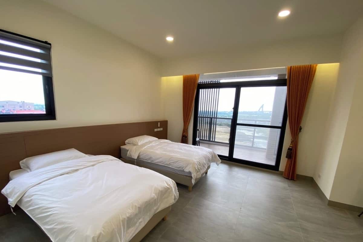 Una habitación de hotel con dos camas, un ventanal con cortinas y vistas al aeropuerto.