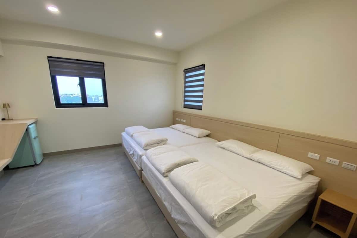 Un dormitorio con una cama, un escritorio y dos ventanas.