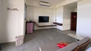 A modern living room with a flat-screen TV mounted on the wall, a small pink refrigerator, and a wooden cabinet. - Sky BnB (Donggang)