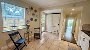 Une pièce comprenant une chaise, une petite table avec un vase et une porte donnant sur une autre pièce.