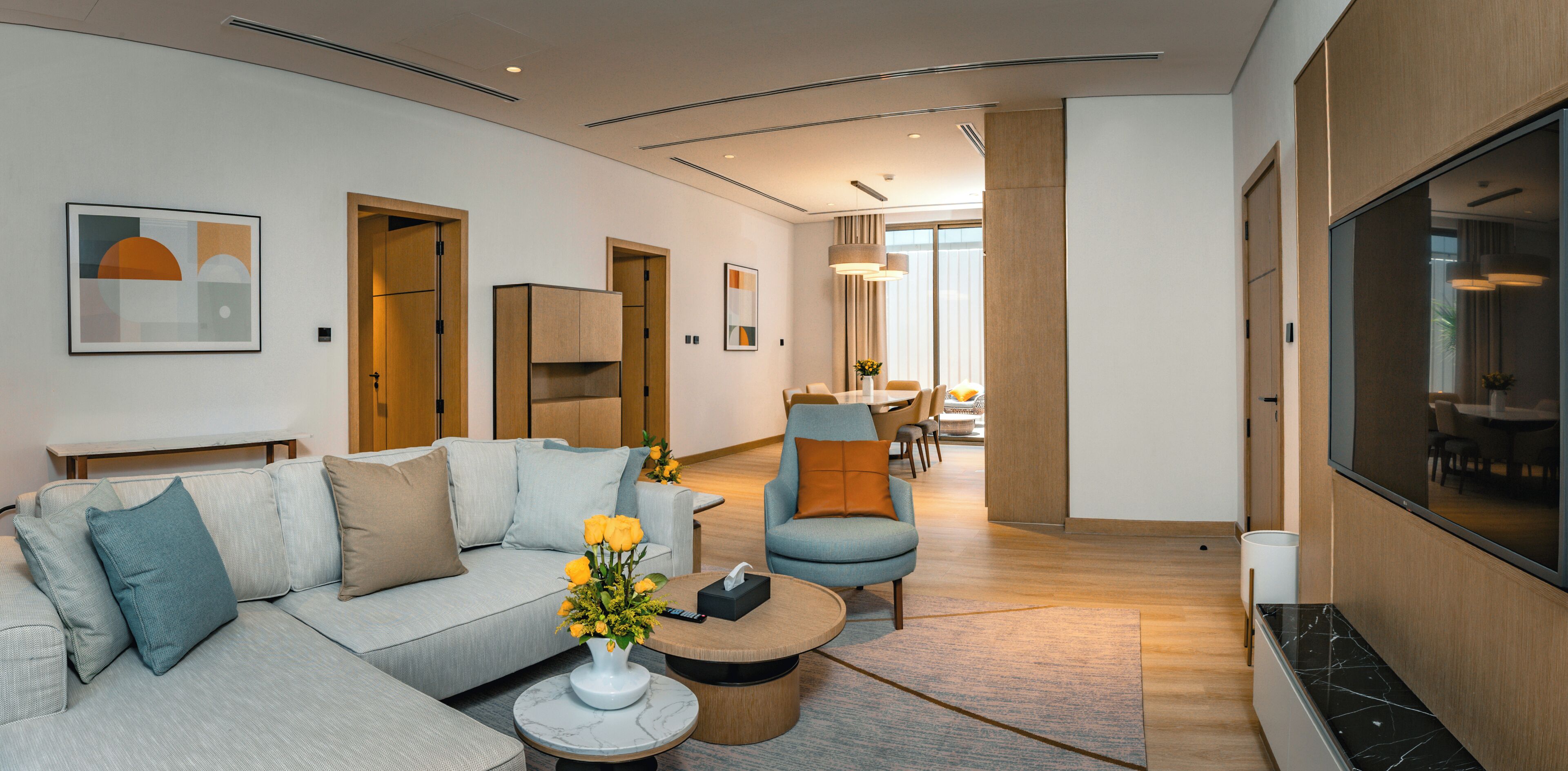 Ein modernes Wohnzimmer mit einer Couch, einem Couchtisch und einem Fernseher. Es gibt Türen zu anderen Räumen.