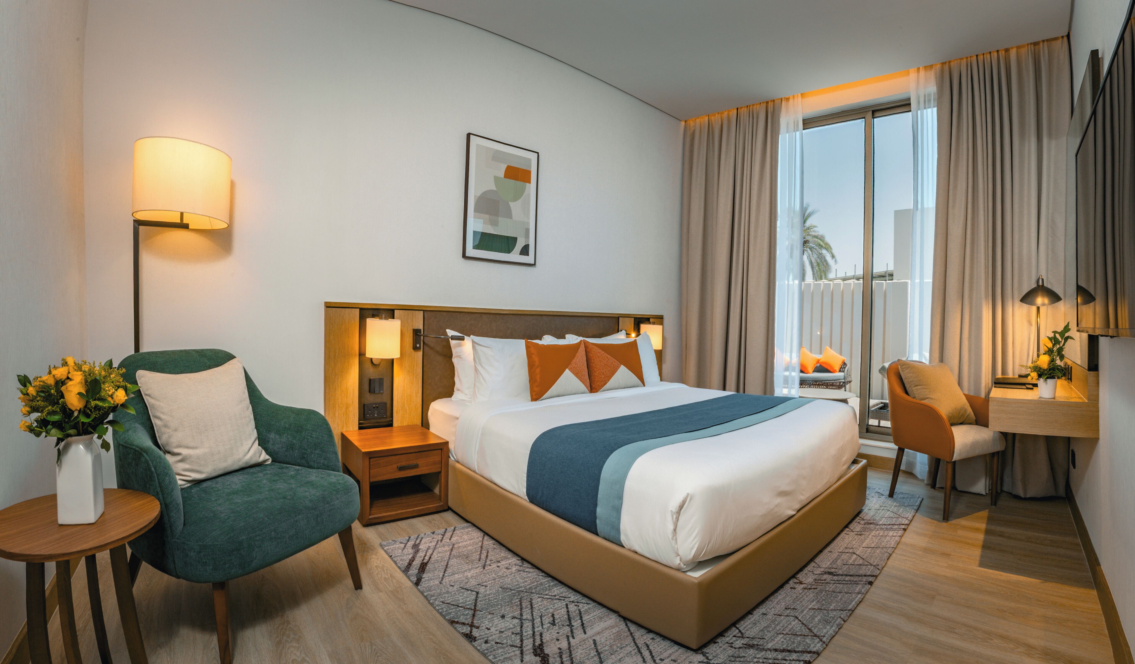 Una habitación de hotel moderna con una cama grande, un escritorio, una silla, una mesita de noche y una ventana con cortinas.