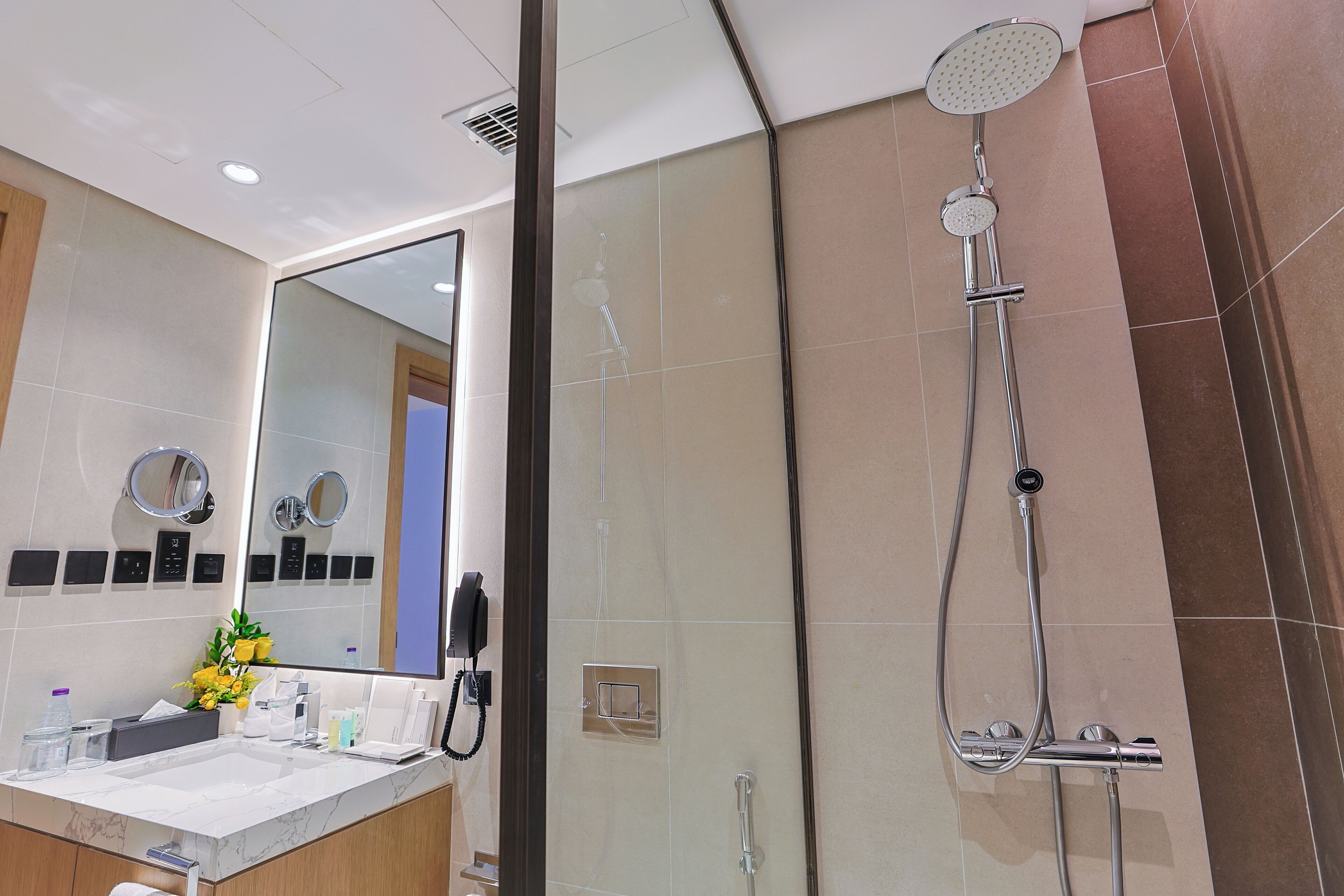 Un baño moderno con un espejo grande, una ducha y un lavamanos.