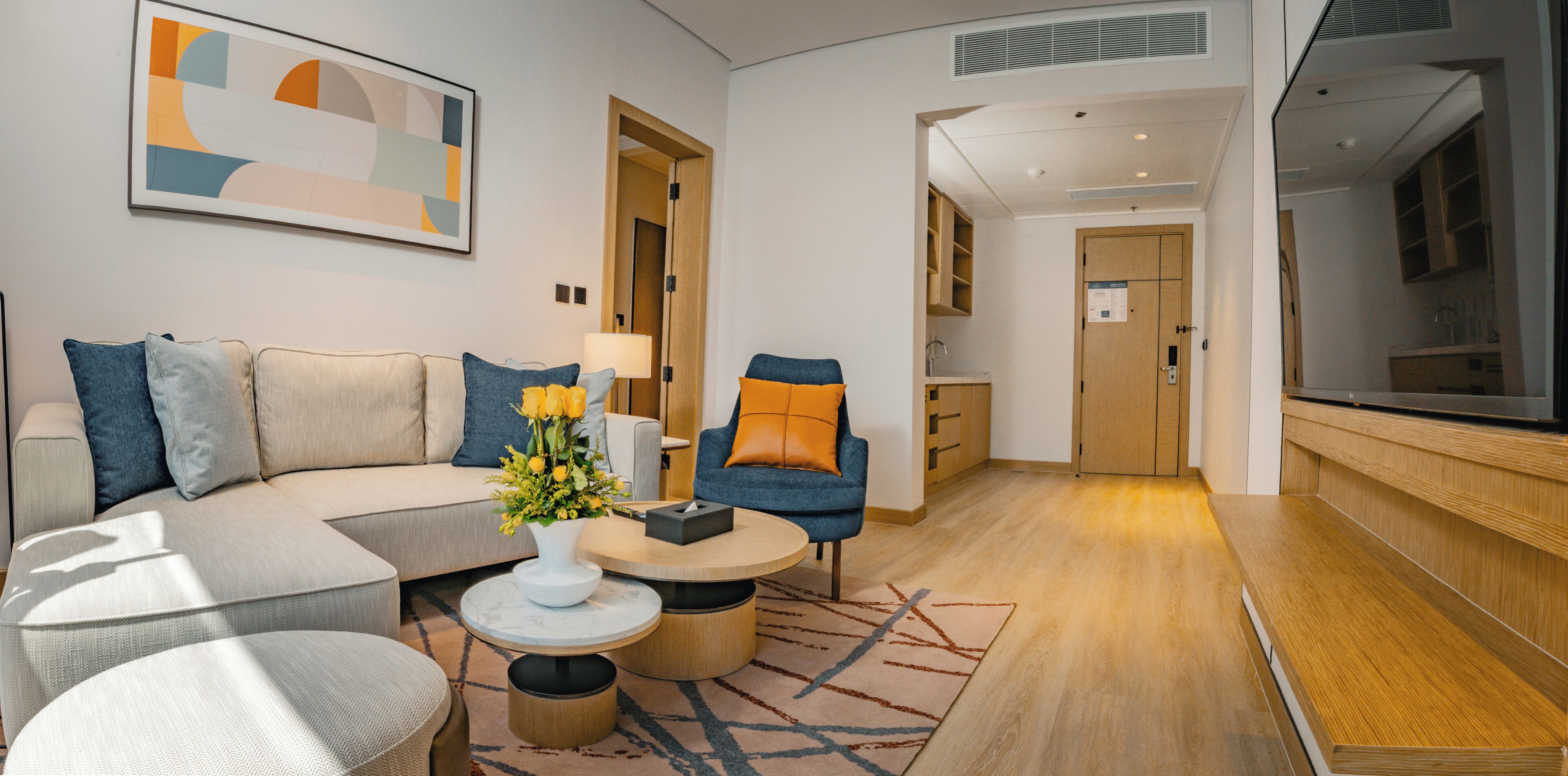 Un salon moderne comprenant un canapé, des fauteuils, une table basse et un téléviseur.