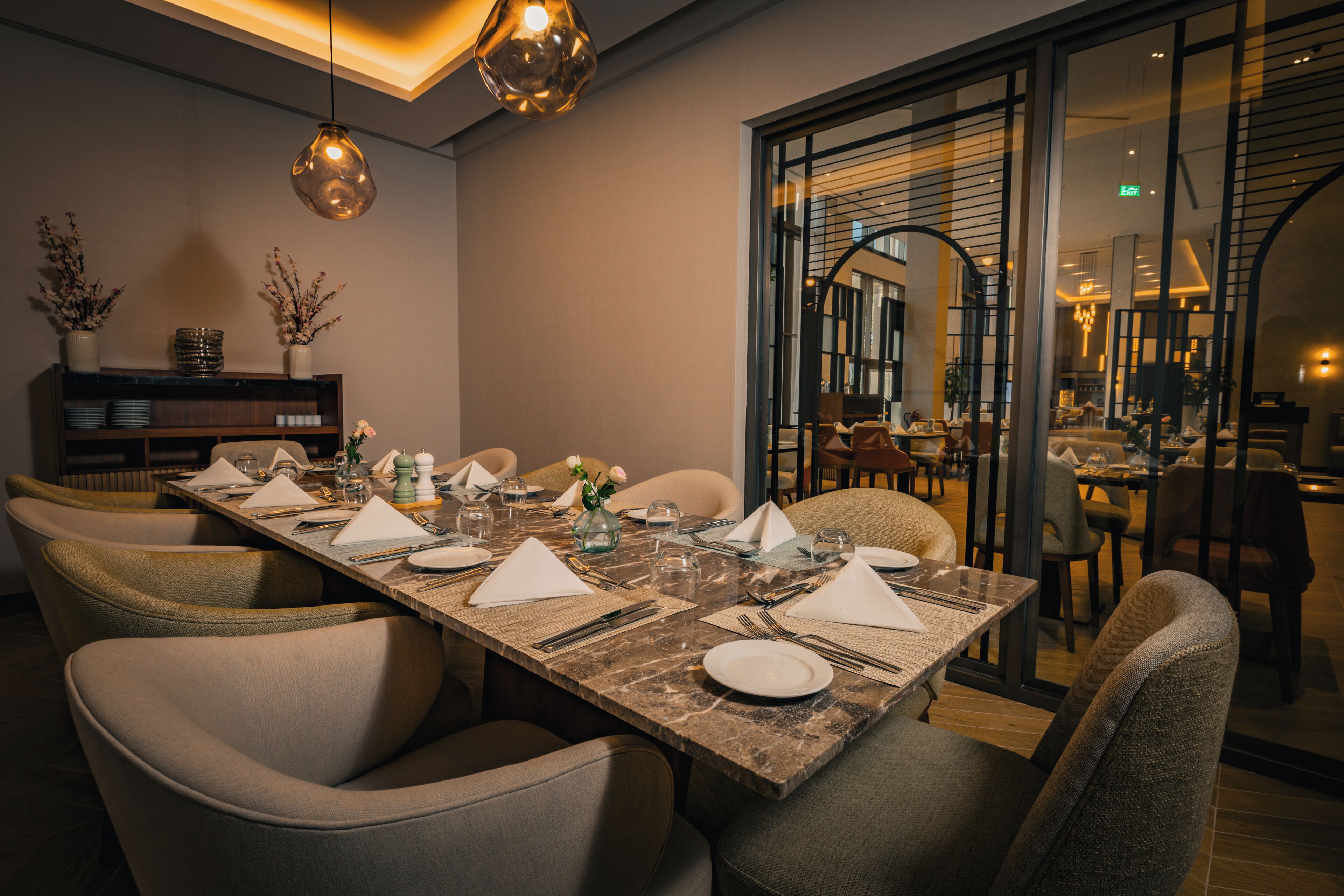 Un espace repas avec une longue table dressée pour le repas, entourée de chaises rembourrées.