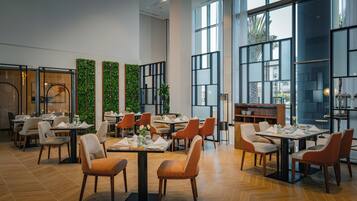 Un restaurant spacieux avec de hauts plafonds, de grandes fenêtres et un mobilier moderne.
