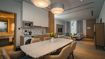 A modern kitchen with a marble countertop, built-in appliances, and a dining area with a table and chairs.