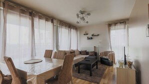 Un salon moderne avec une table à manger, des canapés et un téléviseur.