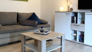 A modern living room with a sofa, a coffee table, a TV, and a bookshelf. - Winterberg gem With Pool, Sauna (Winterberg)