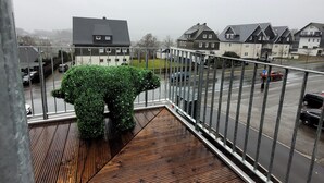 A balcony with a wooden floor and a green hedge. - Winterberg gem With Pool, Sauna (Winterberg)