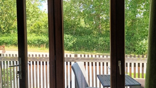 Een kamer met uitzicht op een houten terras en tuinmeubels.