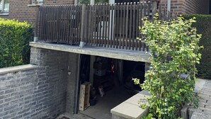 Een huis met twee verdiepingen, een balkon, een garage en een gevel van baksteen.