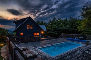 Ein Holzhaus mit Swimmingpool, umgeben von einer Holzterrasse und einem Zaun.