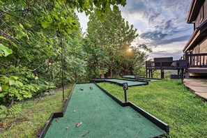 Ein Minigolfplatz mit künstlichem Rasen, Holzkonstruktionen und Bäumen sowie einem Gebäude im Hintergrund.