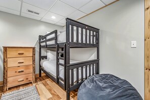 Ein Etagenbett mit Holz-Kopfteil, eine Holzkommode mit Schubladen und ein gemustertes Teppich.