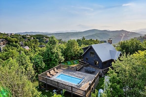 A house with a swimming pool, surrounded by trees and hills. - Lux Gatlinburg Cabin! Mountain Views! Pool! Hot Tub! Arcade! Fire Pit! (Gatlinburg)