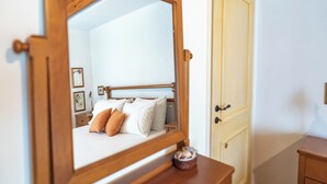 Een slaapkamer met een houten bedframe, wit bedgoed en een nachtkastje met een kaars.