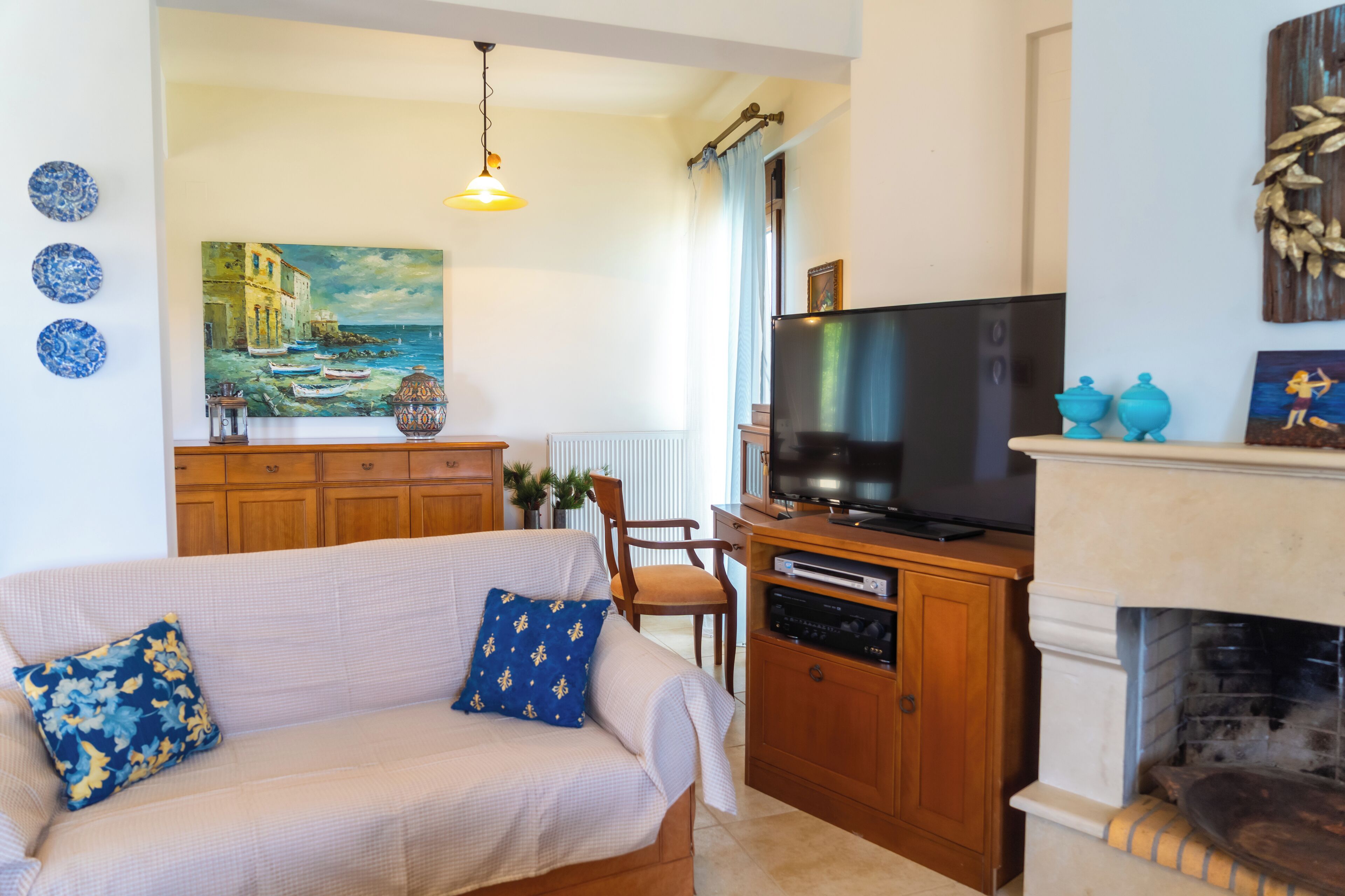 A living room with a sofa, TV, fireplace, and artwork on the wall.