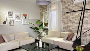 A modern living room with a white sofa, a glass coffee table, and a brick wall. - 6th Of October Signature Stay (6th of October City)