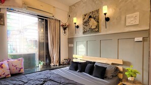 Un dormitorio con cama, ventana con cortinas, ventilador de techo e iluminación en la pared.