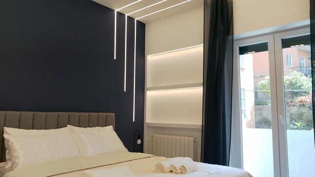 Una habitación de hotel moderna con una cama grande, mesitas de noche, un estante empotrado y vistas al exterior.