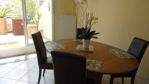 A dining area with a round table, four chairs, a potted plant, and a view through a glass door.