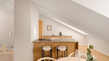 A modern kitchen with a central island, wooden bar stools, and a dining table with chairs.