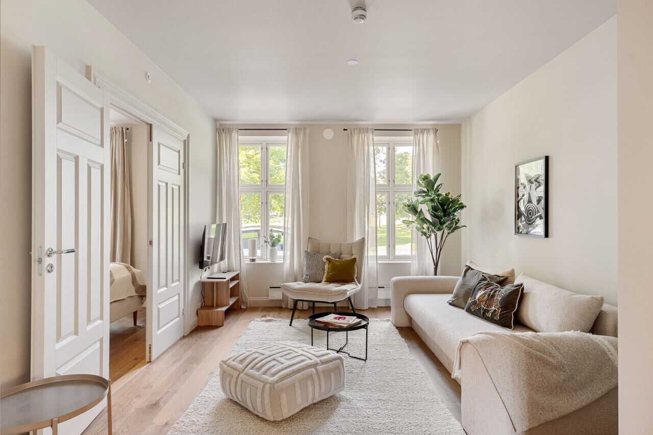A spacious living room with a large window, a sofa, a chair, and a coffee table.