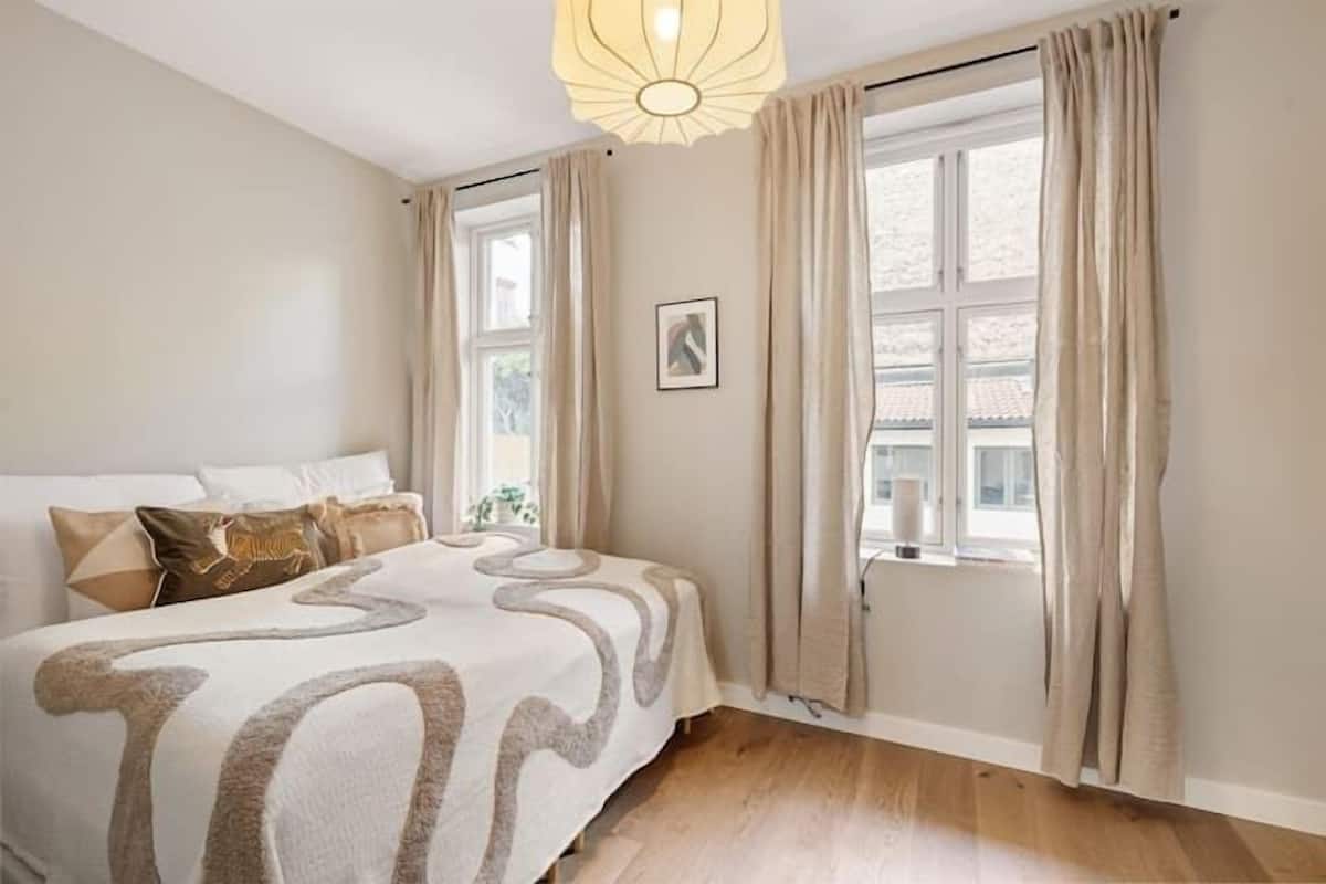 A bedroom with a bed, curtains, a window, and a light fixture.