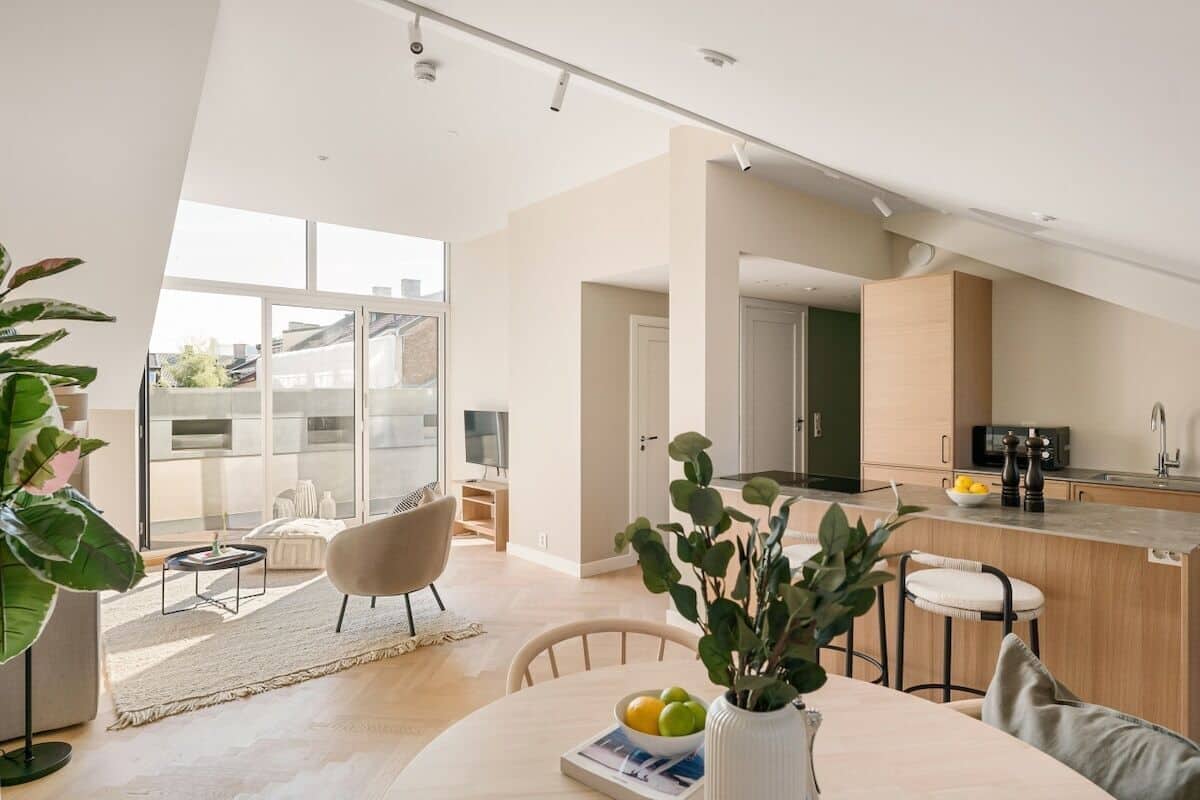 A modern apartment with a dining area, kitchen, and a large window overlooking the city.