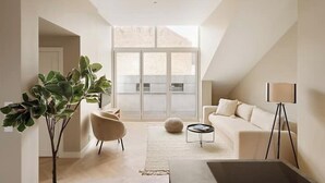 Una sala de estar moderna con un ventanal grande, un sofá, una mesa de centro y una lámpara de pie.