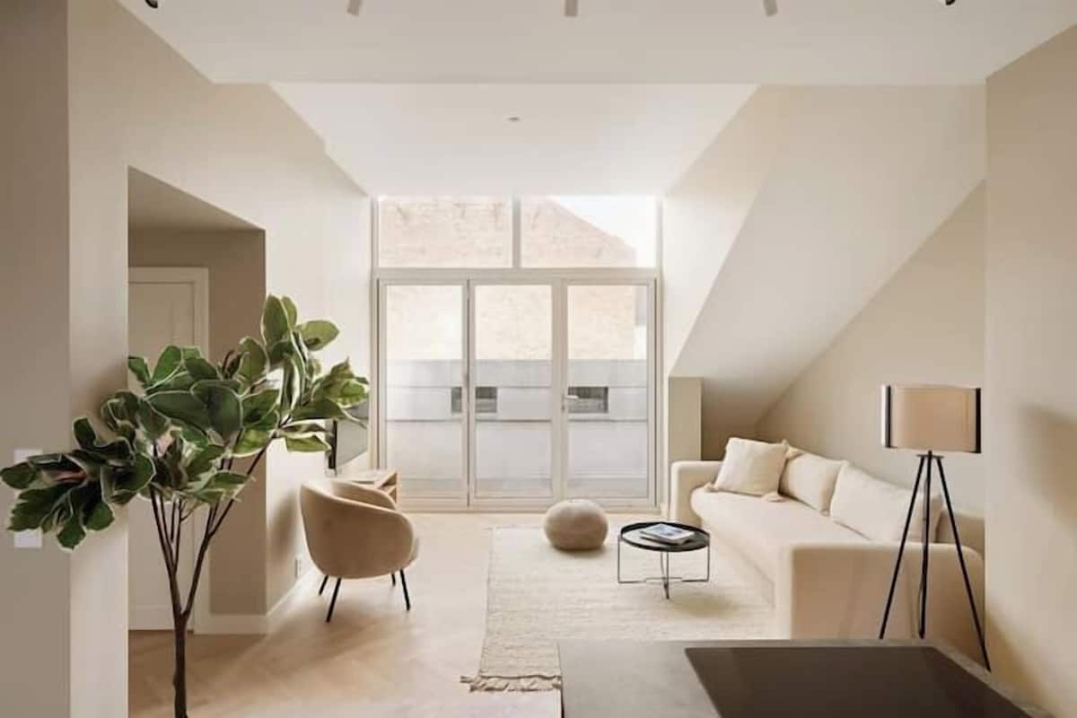 A modern living room with a large window, a sofa, a coffee table, and a floor lamp.