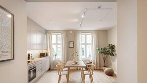 Una cocina moderna con armarios blancos, una mesa de comedor con cuatro sillas y un amplio ventanal con cortinas.
