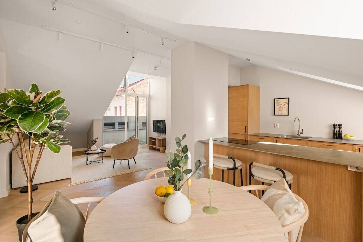 A modern kitchen with a central island, wooden cabinets, and a dining area with a round table and chairs.