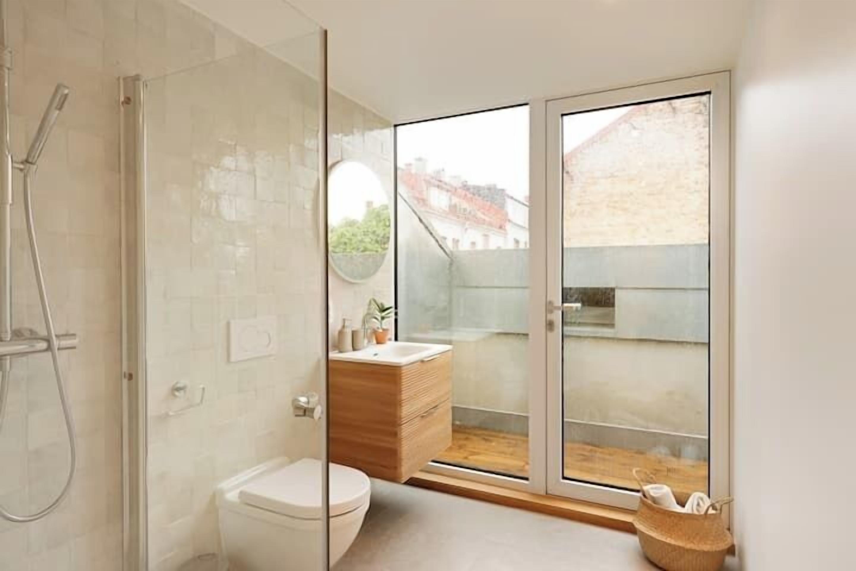 A modern bathroom with a glass shower enclosure, a wooden vanity, and a toilet.