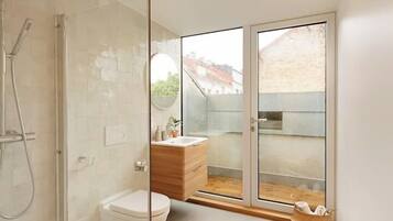 A modern bathroom with a glass shower enclosure, a wooden vanity, and a toilet.