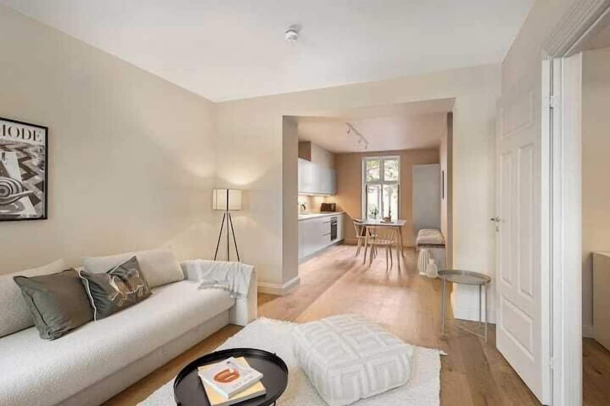 A modern living room with a sofa, a coffee table, and a dining area with a table and chairs.