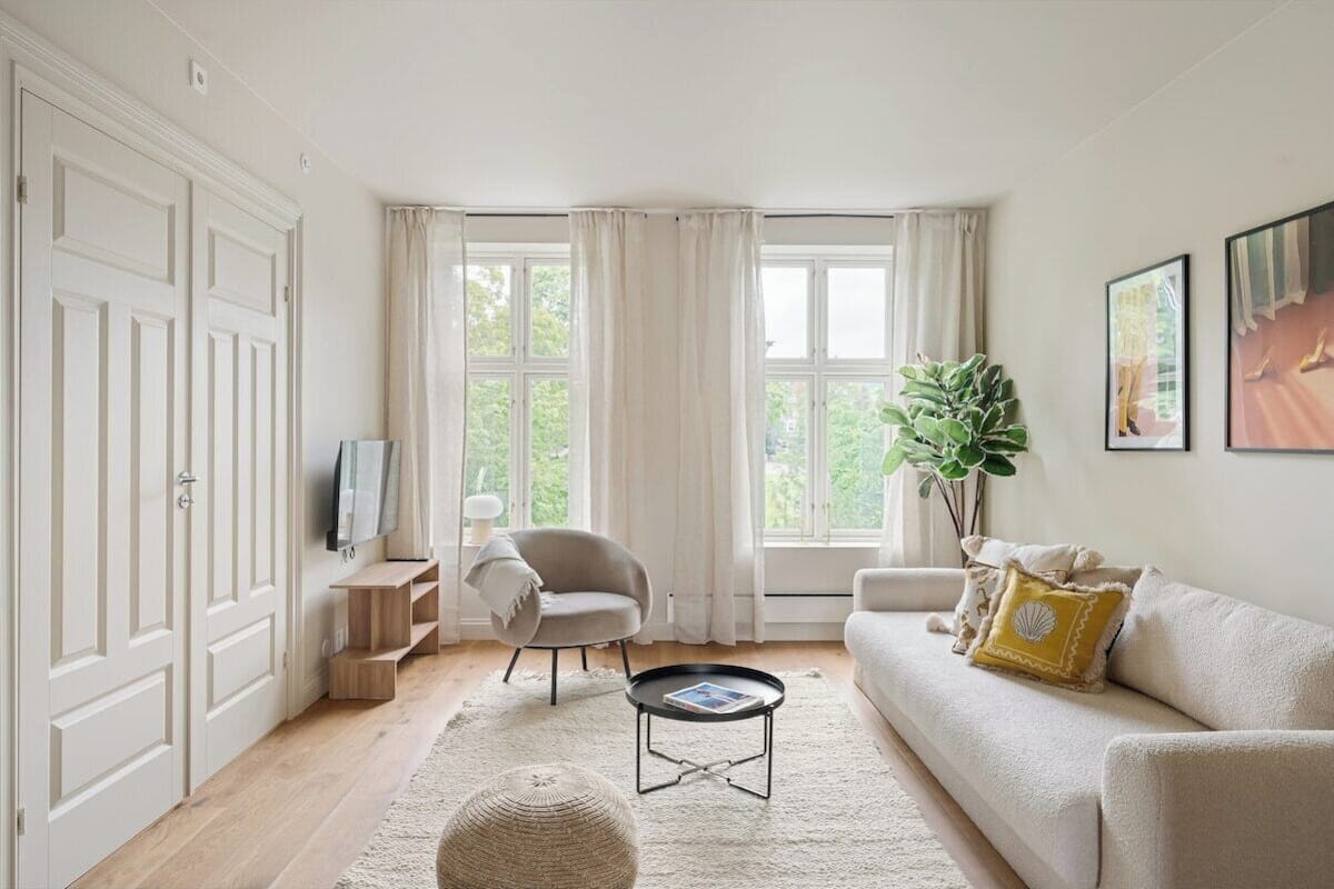 A living room with a sofa, armchair, coffee table, and a TV on a stand.