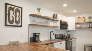 A modern kitchen with wooden countertops, white cabinetry, a built-in microwave, and a coffee maker. - Boomerang 202: New remodel! (Telluride)