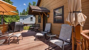 A wooden deck with outdoor furniture, a barbecue grill, and a covered area with a pergola.