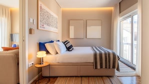 A modern bedroom with a bed, bedside table, lamp, and artwork on the wall.